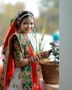 Smiling Indian bride in colorful traditional attire with henna and jewelry, captured outdoors.