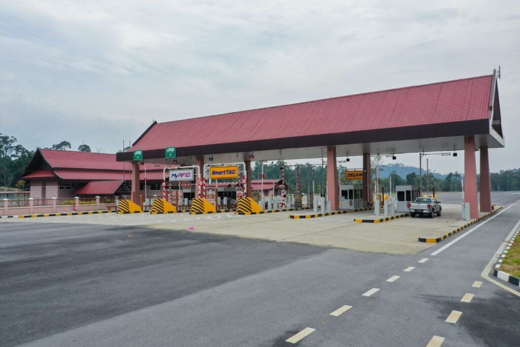 An empty toll plaza on a highway featuring electronic payment lanes and a distinctive red roof.